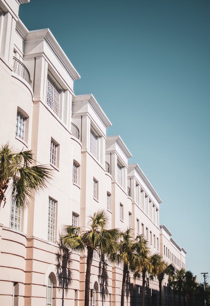 fachada-hotel Edificio moderno de color tonos crema con palmeras en frente y un cielo azul despejado