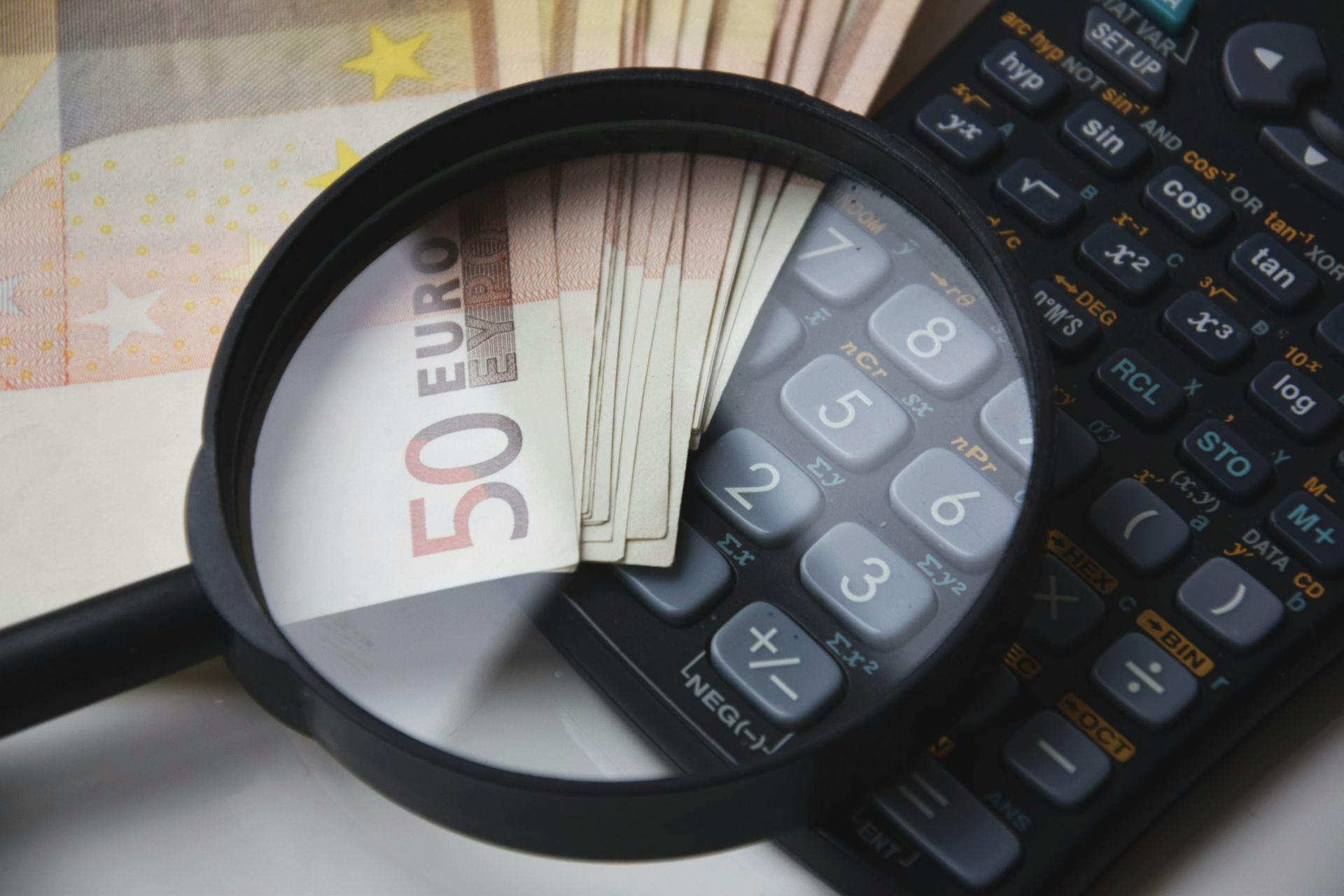 Una lupa sobre billetes de 50 euros y una calculadora