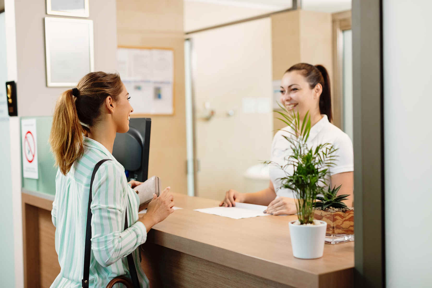 Mujer sonriente hablando con la recepcionista de un hotel