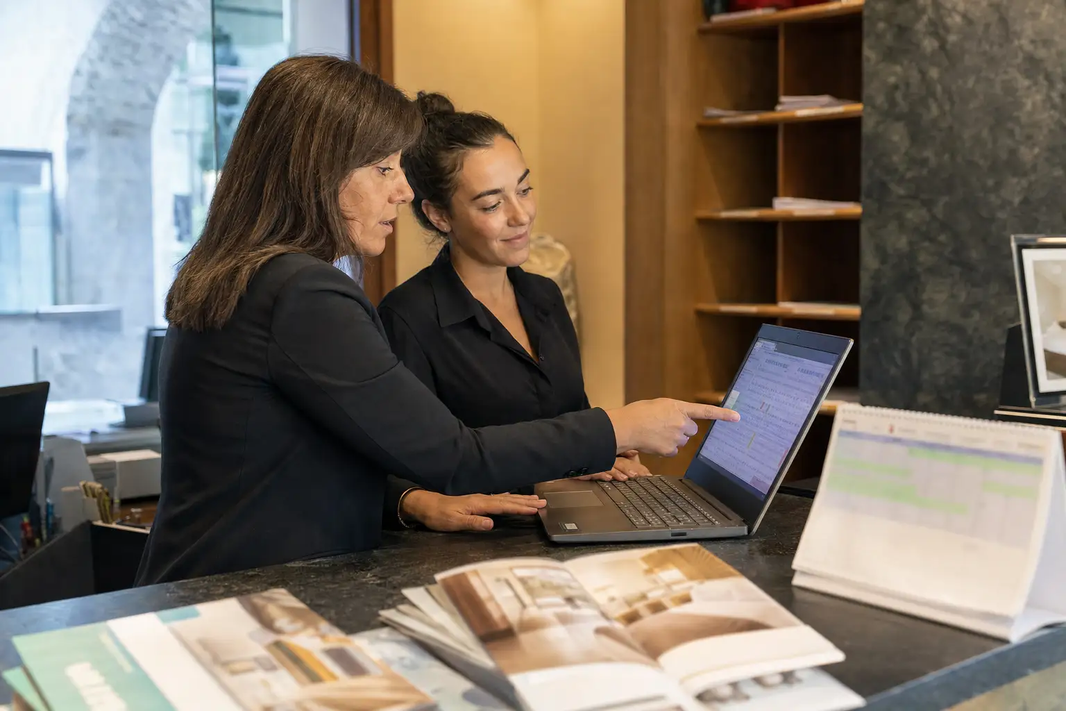 Equipo de hotel revisando tarifas flexibles en un portátil de recepción.
